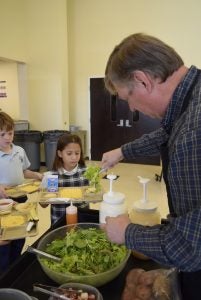 Randy Cox, a Master Gardener who runs Sacred Heart's 4-H Club, dishes out salad during lunch Friday. The lettuce and many of the salad toppings were grown by students. Rebecca Rider/Salisbury Post